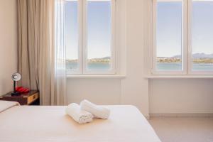 a bedroom with two towels on a bed with windows at Hotel De Plam in Olbia