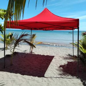 Tenda rossa su una spiaggia sabbiosa con oceano di Villa Las Mellizas a Puerto Armuelles