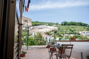 un patio con mesa, sillas y sombrilla en Terrazza Mediterranea en Vietri