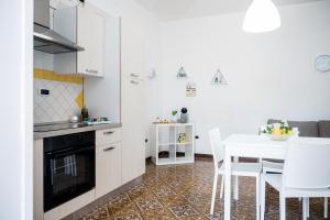 cocina con armarios blancos, mesa y sillas blancas en Terrazza Mediterranea en Vietri