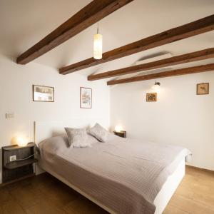 una camera da letto con un letto, pareti bianche e travi in legno di Tiny house Laurel a Kostrena (Costrena)