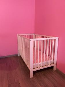 um berço num quarto com uma parede rosa em Schirmeck Apartment em Estrasburgo