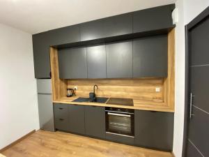 a kitchen with black cabinets and a sink at EM Room in Kraków
