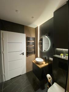 a bathroom with a white sink and a mirror at EM Room in Kraków