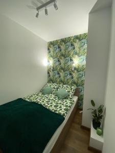 a bedroom with a green bed with a green wall at EM Room in Kraków