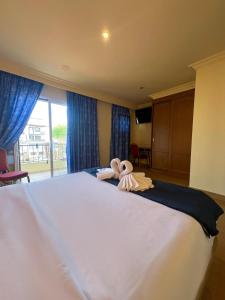 un grande letto bianco con un animale di peluche seduto sopra di Hotel Portofino by InsideHome a Empuriabrava