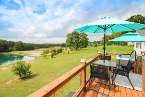 a deck with two chairs and a table with an umbrella at Cozy Alabama Retreat with Hot Tub, Near Ruby Falls! in Bryant