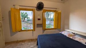 1 dormitorio con ventanas amarillas y 1 cama azul en HOSTEL DA LÚ en Pirenópolis