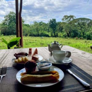 a table with two plates of food and a cup of coffee at Hotel Bird Paradise in Sigiriya