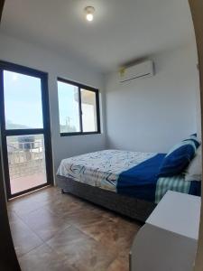 a bedroom with a bed and two large windows at Portal de la Sierra Apto 207 in Playa Dormida