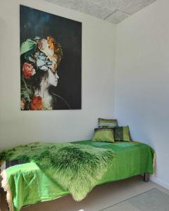 a bedroom with a green bed with a painting on the wall at Charmerende villalejlighed på 80 kvm inklusiv gårdhave in Viby