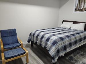a bedroom with a bed and a blue chair at Feel At Home in Edmonton