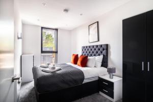 1 dormitorio con 1 cama grande con almohadas de color naranja en Modern 3 Bedroom Manchester Apartment, en Mánchester