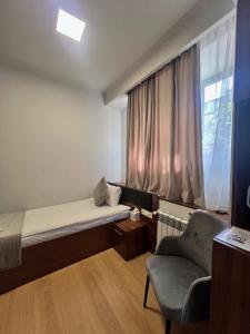a small room with a bed and a chair and a window at Mashtots Hotel in Yerevan