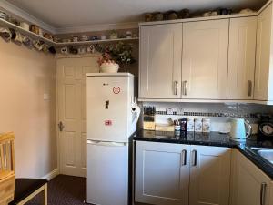 La cuisine est équipée de placards blancs et d'un réfrigérateur blanc. dans l'établissement Private Apartment in Windsor, à Windsor