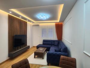 een woonkamer met een blauwe bank en een tv bij Eleven Apartment in Podgorica