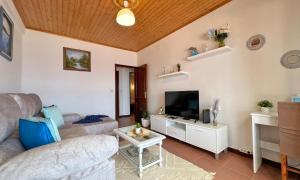 a living room with a couch and a tv at Maiata Beach House by HR Madeira in Porto da Cruz