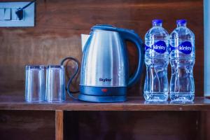 a tea kettle and water bottles on a shelf at Delhi Height Kasol - Cafe and Hotel in Kasol