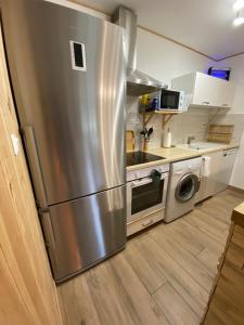 eine Küche mit einem Kühlschrank aus Edelstahl und einem Geschirrspüler in der Unterkunft Petit cocon comme a la maison in Villard-de-Lans