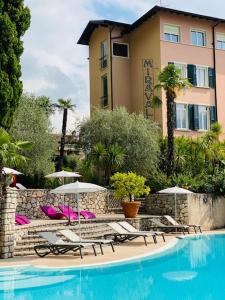 a pool with chairs and umbrellas in front of a hotel at La Casa al Torrente in Riva del Garda