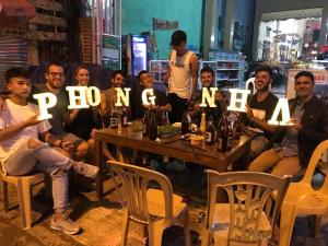 a group of people sitting around a table holding up signs at Bee Backpackers Hostel in Quang Binh