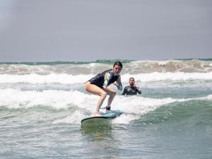 una persona montando una ola en una tabla de surf en el océano en La Posada - Hostel en Santa Teresa Beach