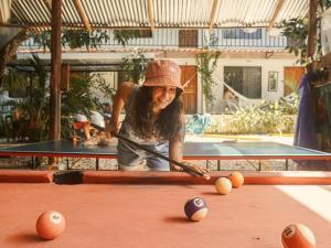 een vrouw die pool speelt met een keu op een pooltafel bij La Posada - Hostel in Santa Teresa Beach