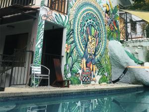 een gebouw met een kleurrijke muurschildering naast een zwembad bij La Posada - Hostel in Santa Teresa Beach