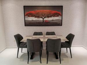 a dining room table with chairs and a red tree at Corniche Tower in Ajman 