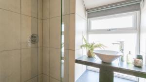La salle de bains est pourvue d'un lavabo, d'une douche et d'une fenêtre. dans l'établissement Ty Lawr, à Baie de Cemaes