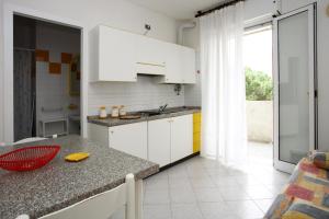 cocina con armarios blancos y encimera en Residence La Pigna, en Rosolina Mare
