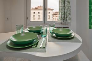 Attico di Piazza Cima في كونيليانو: طاولة بيضاء مع طبقين خضراء وكؤوس