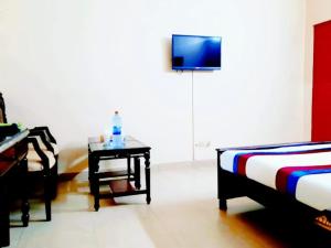 Calming Residence في لاهور: غرفة بسرير وطاولة مع تلفزيون
