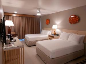 ein Hotelzimmer mit 2 Betten und einem TV in der Unterkunft Fiesta Resort All Inclusive Central Pacific - Costa Rica in El Roble