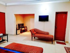 Calming Residence في لاهور: غرفة معيشة بأثاث احمر وتلفزيون بشاشة مسطحة