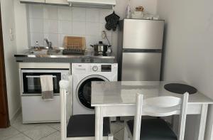 uma cozinha com uma mesa e um frigorífico branco em ALEKA KOTSI ROOMS em Igoumenitsa