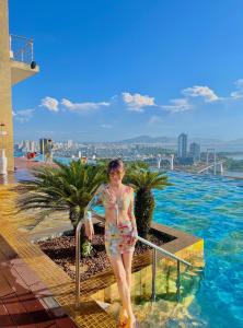 a woman standing on the side of a swimming pool at Luxury Ocean View Danang Golden Bay in Da Nang