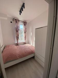 a small bedroom with a bed and a window at J.D Apartment in Gniezno