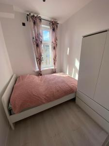 a small bedroom with a bed and a window at J.D Apartment in Gniezno