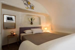 une chambre avec un lit et un miroir dans l'établissement Strogili, à Oia 133 autres photos