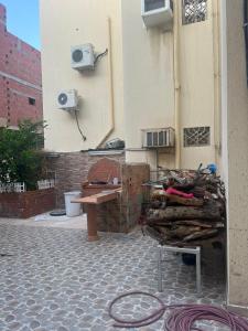 a bench sitting next to a building with a pile of wood at فيلا دورين وملحق in Miná