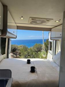 Beautiful Campervan (Mallorca) في San Francesch: كوبين يجلسون على سرير في الجزء الخلفي من سيارة فان