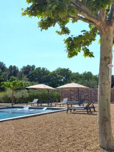 een groep banken en parasols naast een zwembad bij Le Mas Joséphine in Saint-Rémy-de-Provence