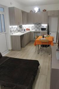 een grote keuken met een oranje tafel en een tafel en stoelen bij Ranias's House 2 in Piraeus