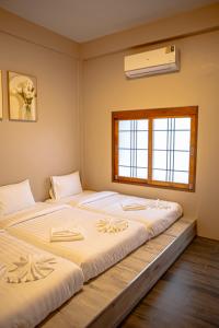 two beds in a room with a window at Miki House in Chumphon