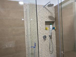 La salle de bains est pourvue d'une douche avec une porte en verre. dans l'établissement Albanian Riviera Appartement, à Vlorë