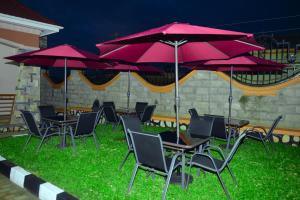 Kelly Traveller's Inn في Kakinzi: مجموعة طاولات وكراسي مع مظلات حمراء