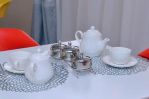 Kelly Traveller's Inn في Kakinzi: طاولة بيضاء عليها أكواب وأدوات الشاي