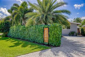 a sign in front of a house with a palm tree at Designer Delight in Fort Lauderdale