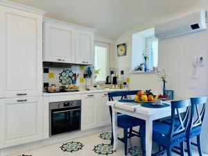 uma cozinha branca com uma mesa e cadeiras azuis em YourHome - White House Giò em Positano